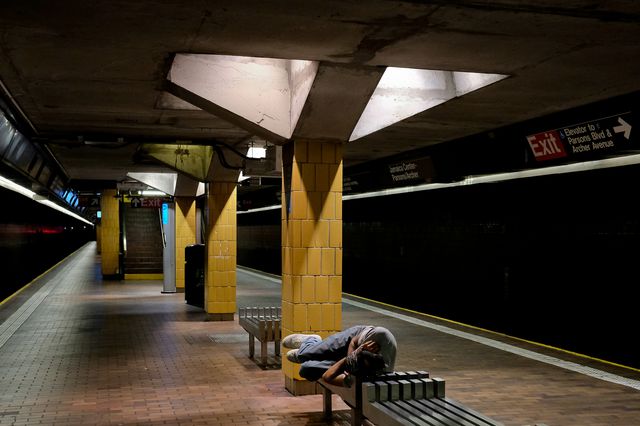 A person sleeps on a subway bench in NYC.